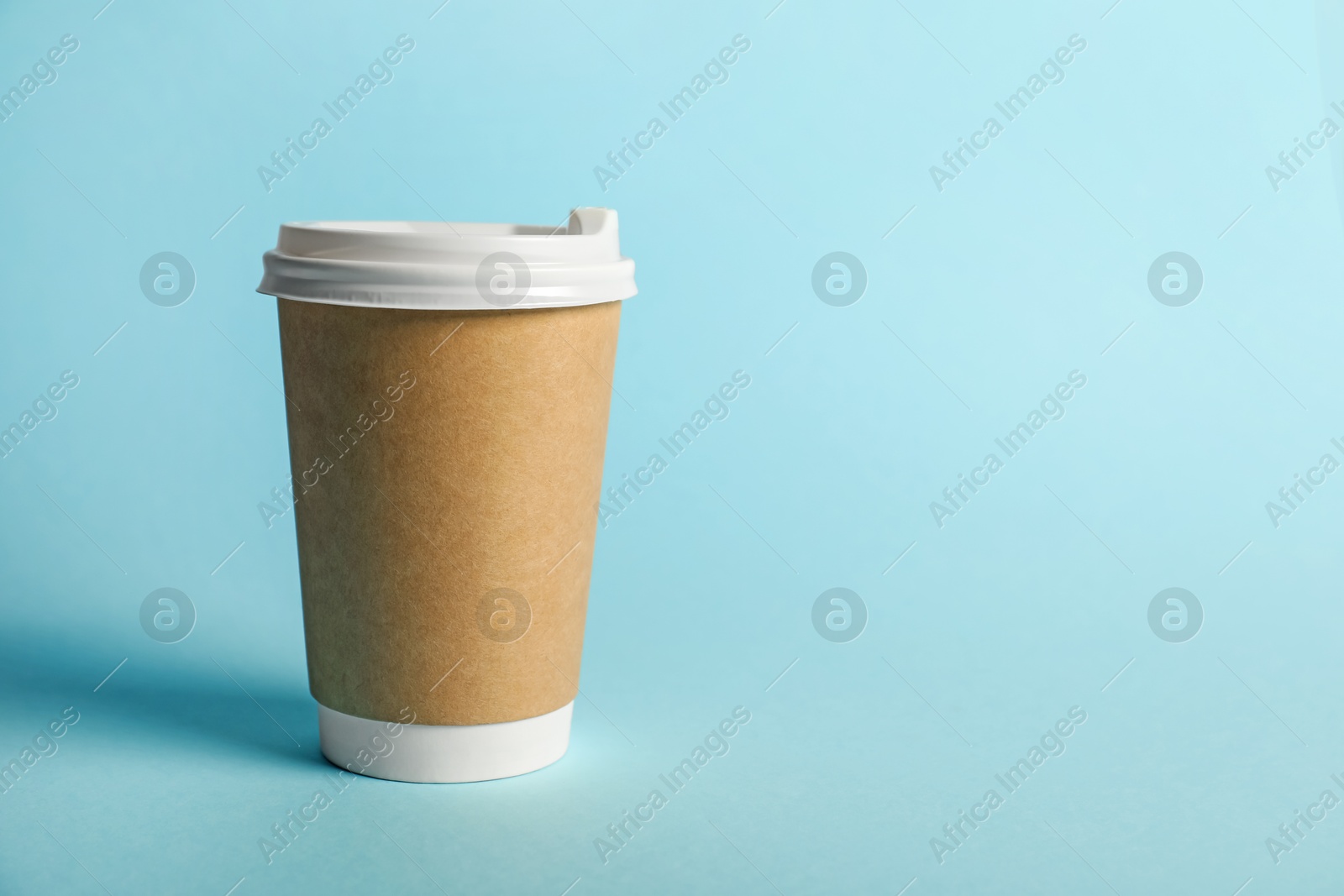 One paper cup on light blue background. Mockup for design Photo of One paper cup on light blue background. Mockup for design