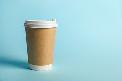 Photo of One paper cup on light blue background. Mockup for design