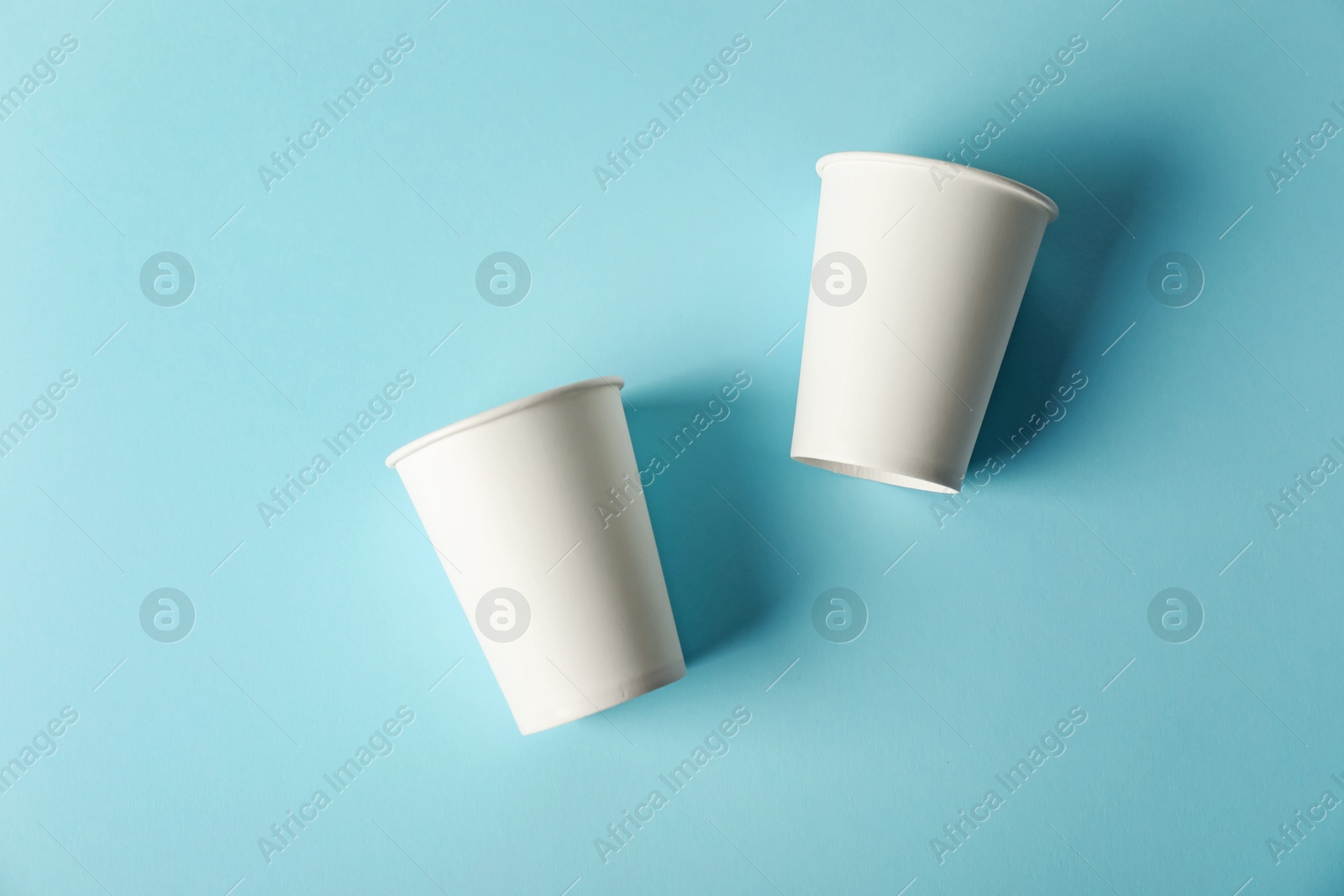 Paper cups on light blue background, flat lay. Mockup for design Photo of Paper cups on light blue background, flat lay. Mockup for design