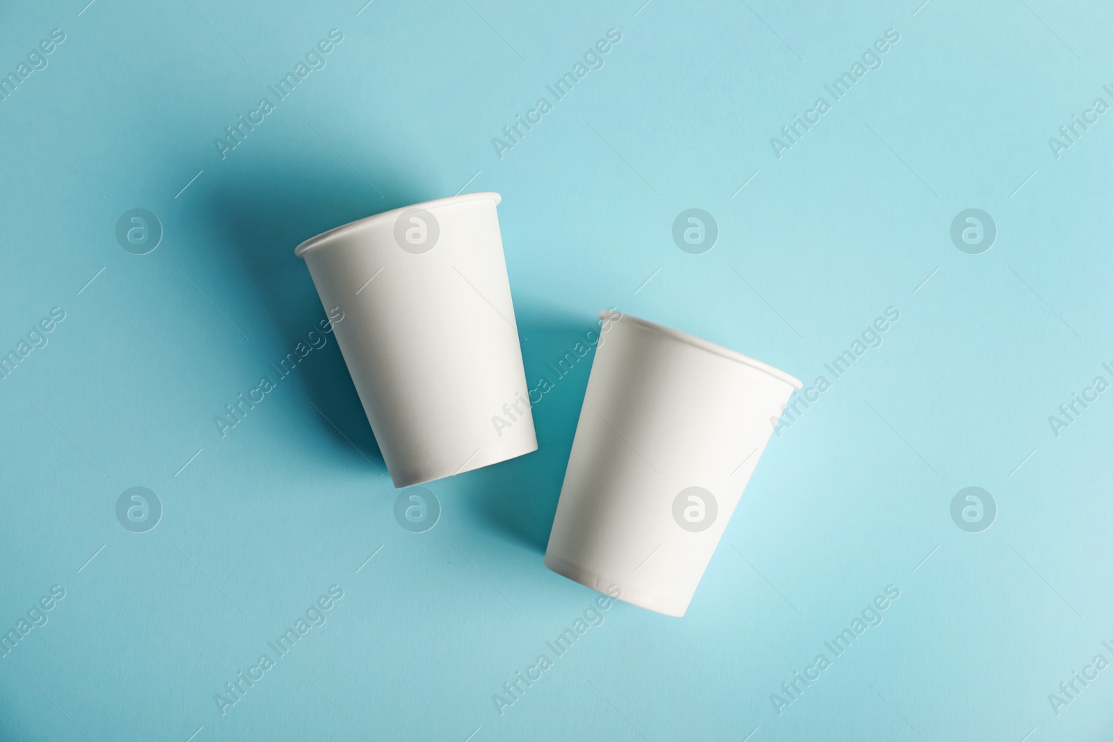 Paper cups on light blue background, flat lay. Mockup for design Photo of Paper cups on light blue background, flat lay. Mockup for design