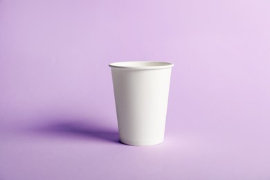 Photo of Paper cup on violet background. Mockup for design