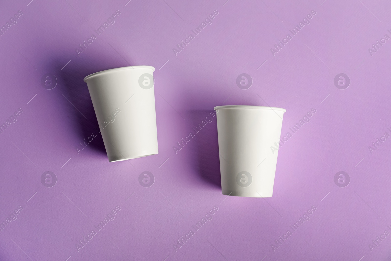Paper cups on violet background, flat lay. Mockup for design Photo of Paper cups on violet background, flat lay. Mockup for design