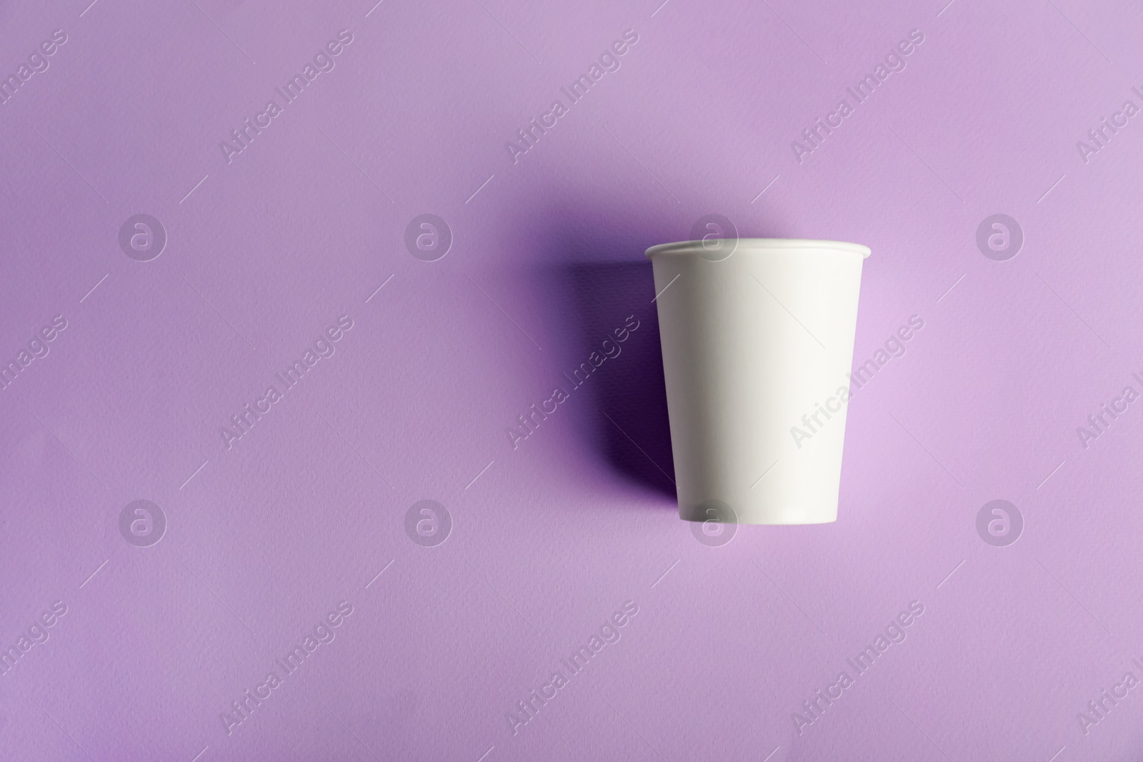 Paper cup on violet background, top view. Mockup for design Photo of Paper cup on violet background, top view. Mockup for design