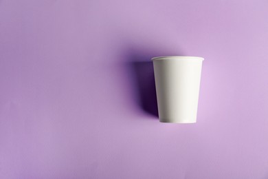 Photo of Paper cup on violet background, top view. Mockup for design