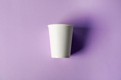 Photo of Paper cup on violet background, top view. Mockup for design