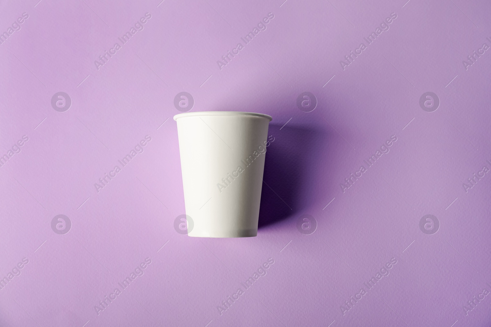 Paper cup on violet background, top view. Mockup for design Photo of Paper cup on violet background, top view. Mockup for design
