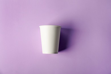 Photo of Paper cup on violet background, top view. Mockup for design