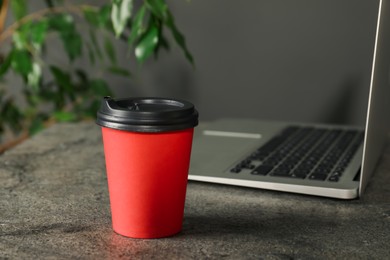 Photo of Paper cup on grey textured table indoors, closeup. Mockup for design