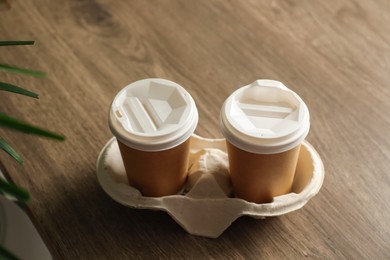Photo of Holder with paper cups on wooden table. Mockup for design