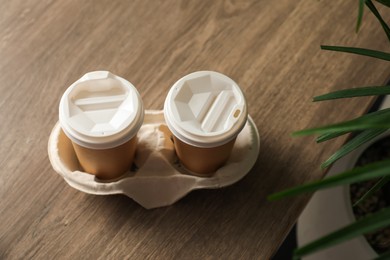 Photo of Holder with paper cups on wooden table, above view. Mockup for design
