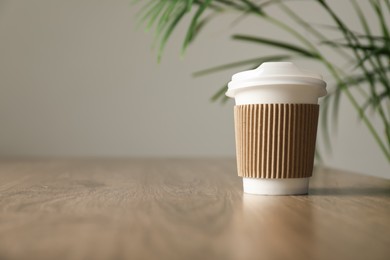 Photo of Paper cup on wooden table in cafe, closeup. Mockup for design
