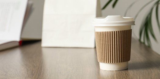 Photo of Paper cup on wooden table in cafe, closeup. Mockup for design