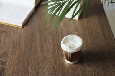 Photo of Paper cup on wooden table. Mockup for design