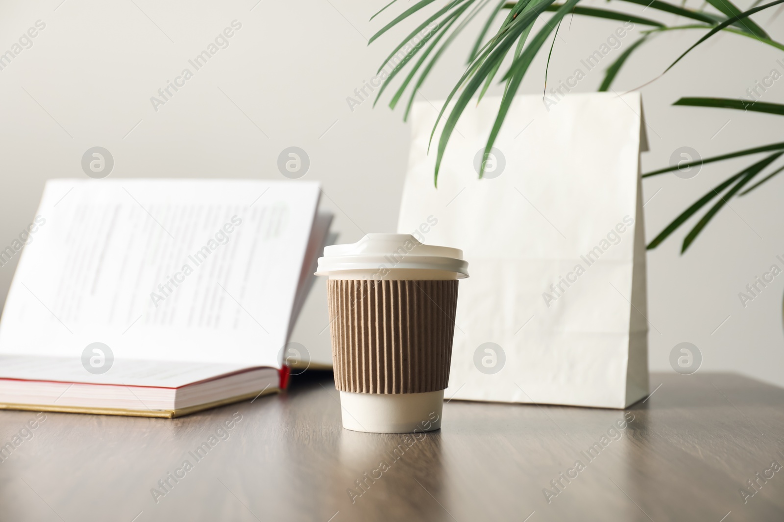 Paper cup, takeaway bag and book on wooden table indoors. Mockup for design Photo of Paper cup, takeaway bag and book on wooden table indoors. Mockup for design