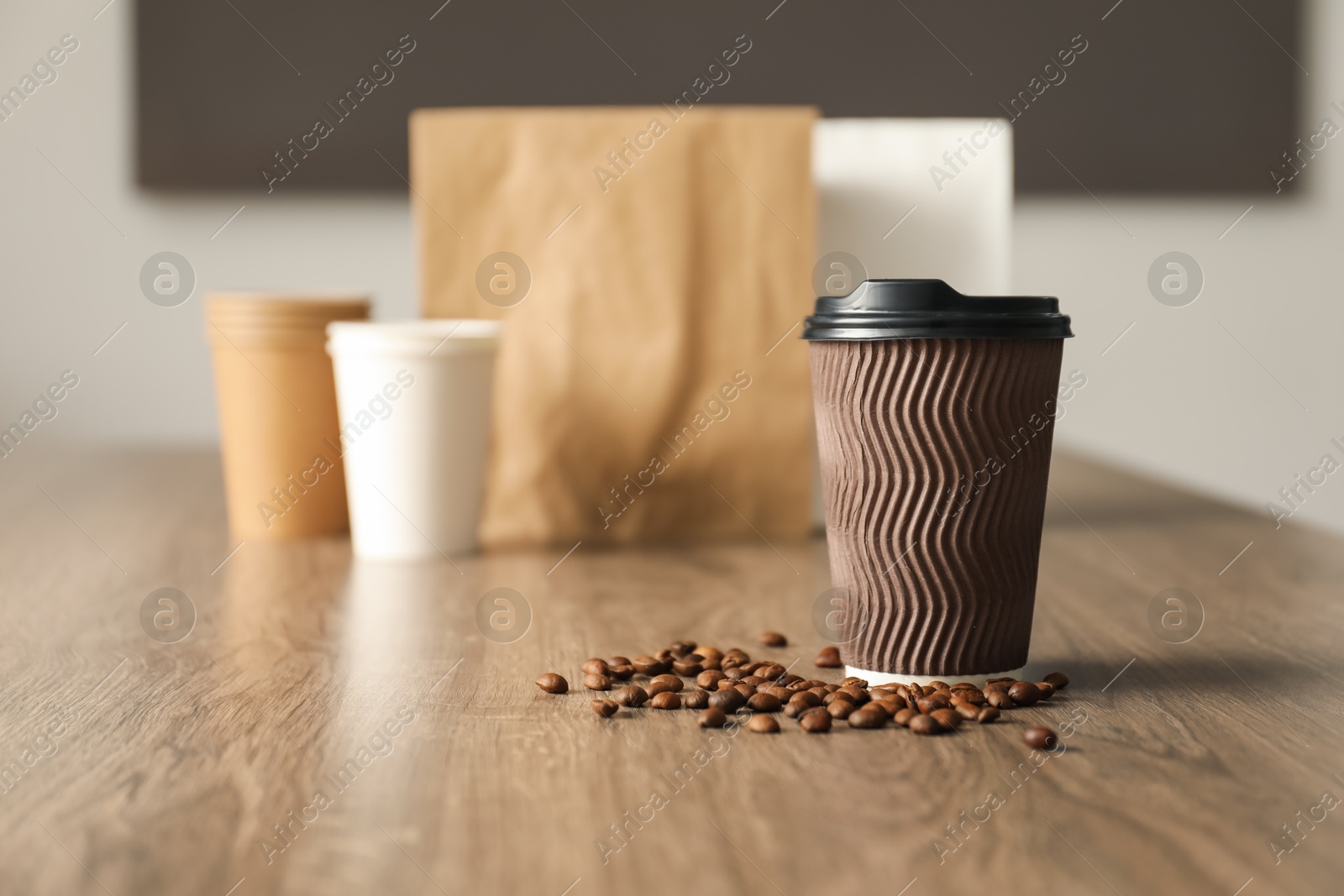 Paper cup and coffee beans on wooden table indoors. Mockup for design Photo of Paper cup and coffee beans on wooden table indoors. Mockup for design