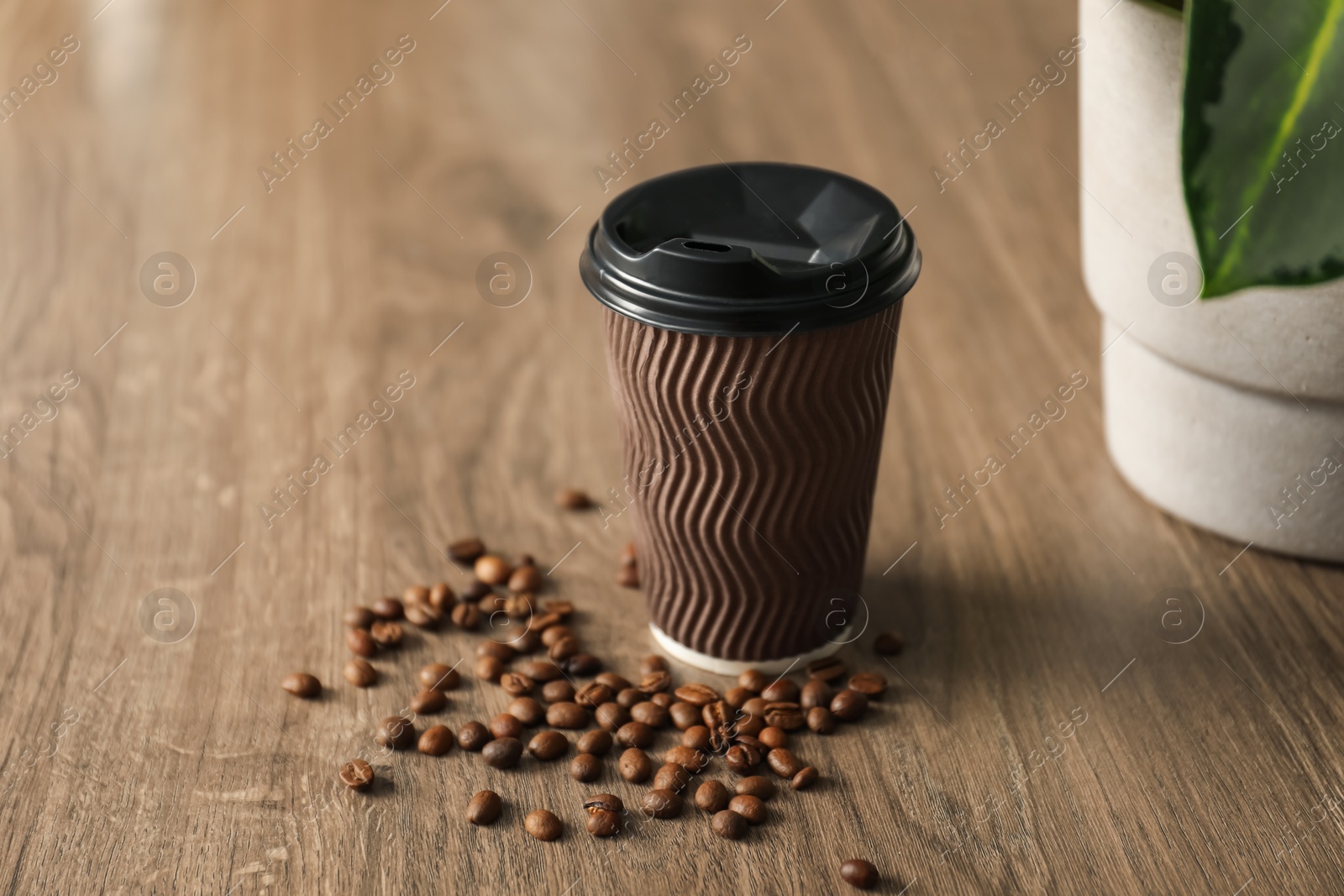 Paper cup and coffee beans on wooden table, closeup. Mockup for design Photo of Paper cup and coffee beans on wooden table, closeup. Mockup for design