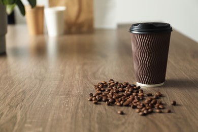 Photo of Paper cup and coffee beans on wooden table indoors. Mockup for design