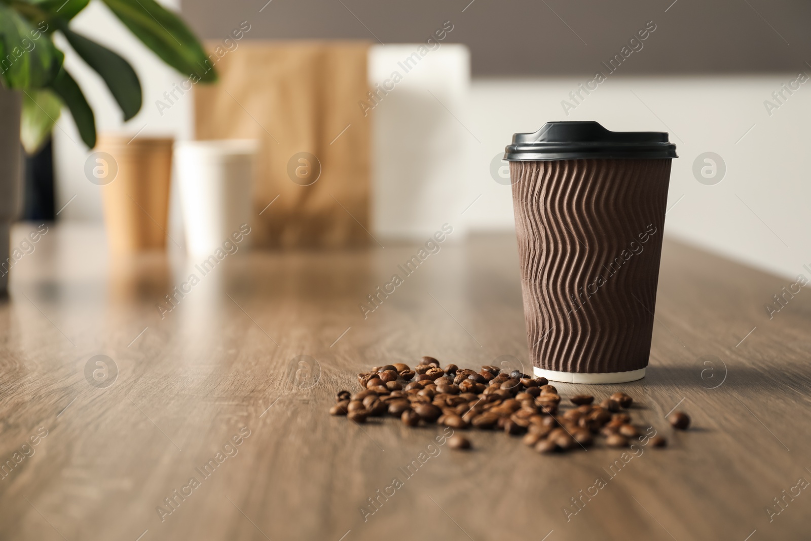 Paper cup and coffee beans on wooden table indoors. Mockup for design Photo of Paper cup and coffee beans on wooden table indoors. Mockup for design