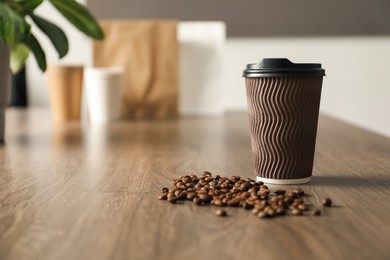 Photo of Paper cup and coffee beans on wooden table indoors. Mockup for design