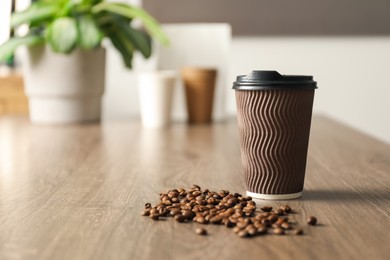 Photo of Paper cup and coffee beans on wooden table indoors. Mockup for design