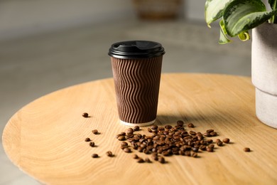 Photo of Paper cup and coffee beans on wooden table indoors. Mockup for design