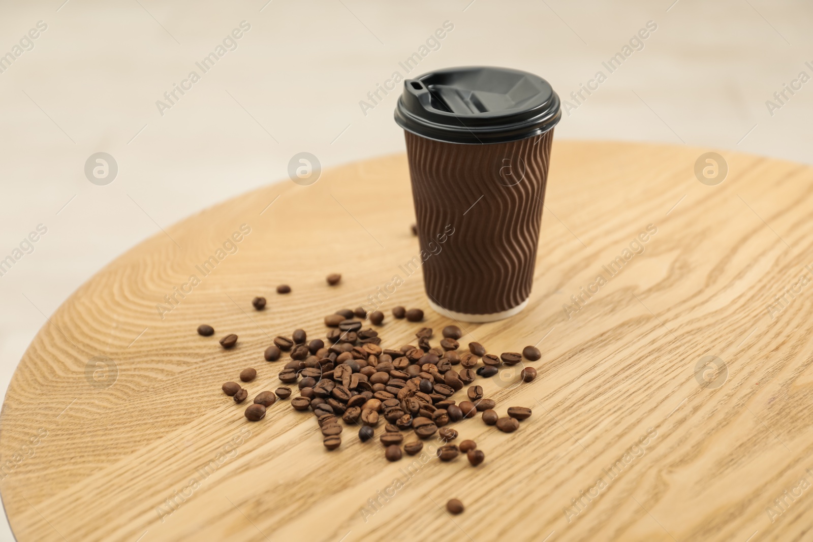 Paper cup and coffee beans on wooden table indoors. Mockup for design Photo of Paper cup and coffee beans on wooden table indoors. Mockup for design