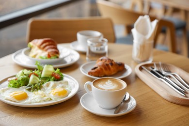 Photo of Delicious breakfast served on wooden table in cafe