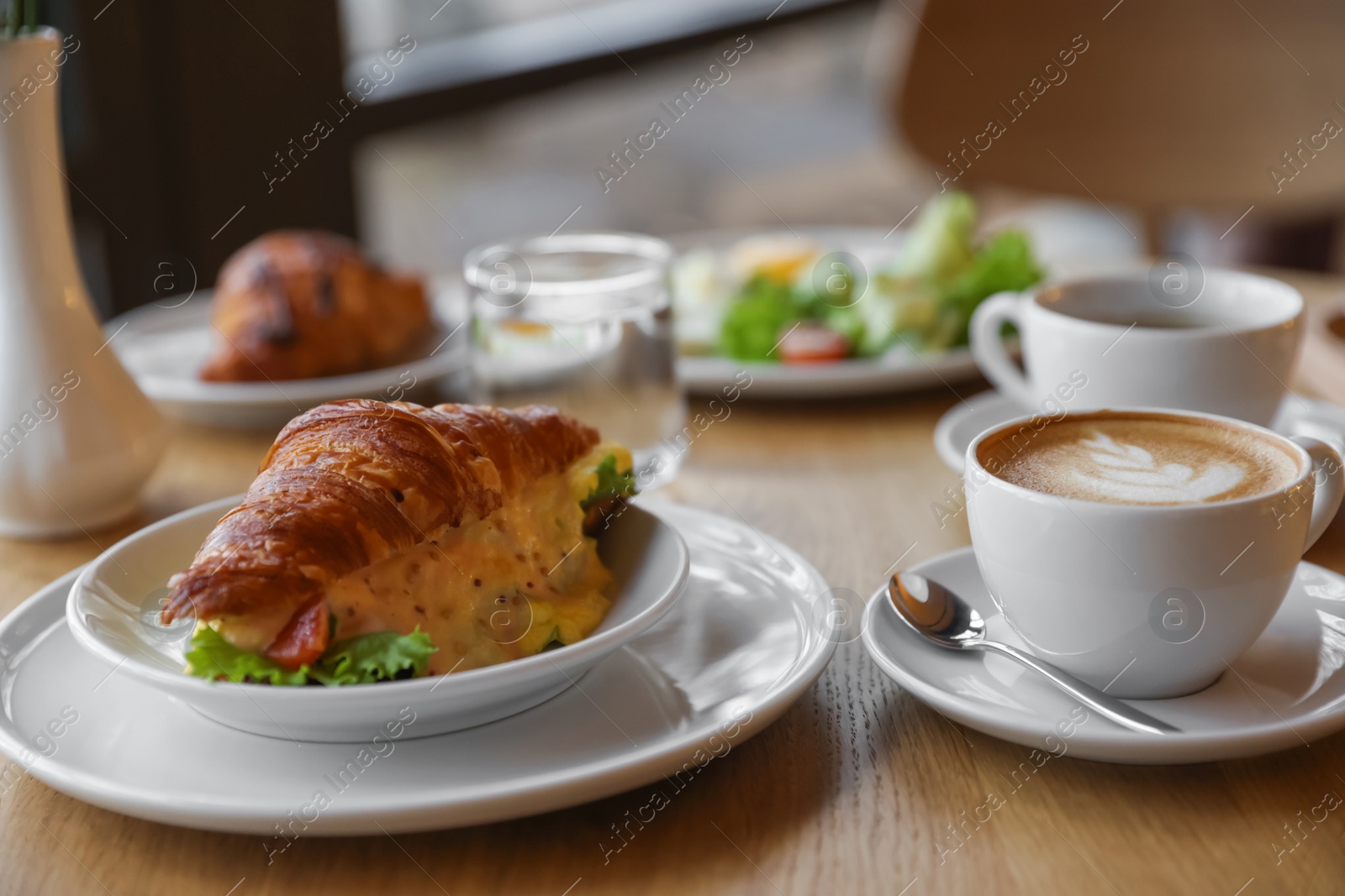 Photo of Delicious breakfast served on wooden table in cafe, closeup