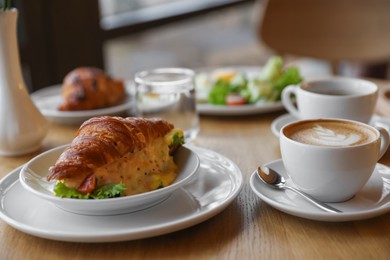 Photo of Delicious breakfast served on wooden table in cafe, closeup