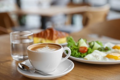 Photo of Delicious breakfast served on wooden table in cafe, closeup