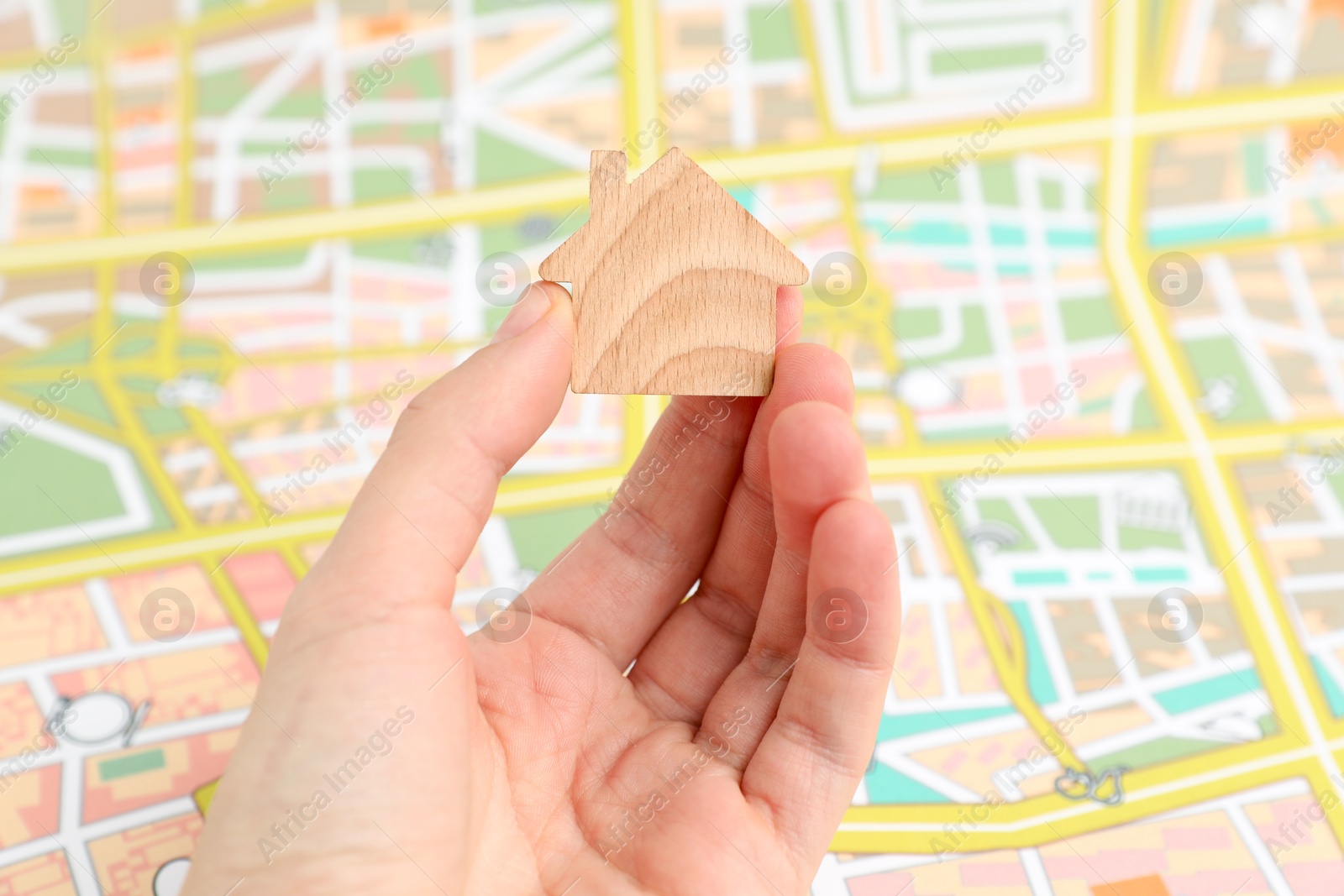 Photo of Woman with wooden house model near city map, closeup. Accommodation search