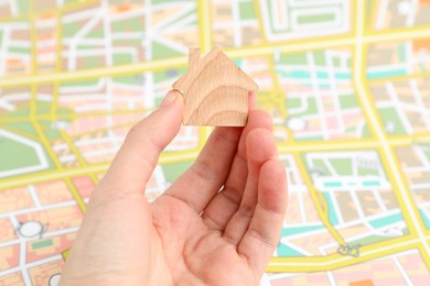 Photo of Woman with wooden house model near city map, closeup. Accommodation search