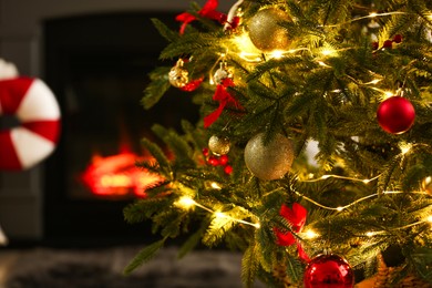 Photo of Beautiful decorated Christmas tree near fireplace at home, closeup. Space for text