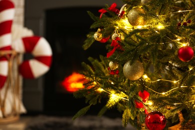 Photo of Beautiful decorated Christmas tree near fireplace at home, closeup. Space for text