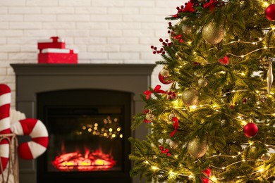 Photo of Beautiful decorated Christmas tree near fireplace at home, closeup. Bokeh effect