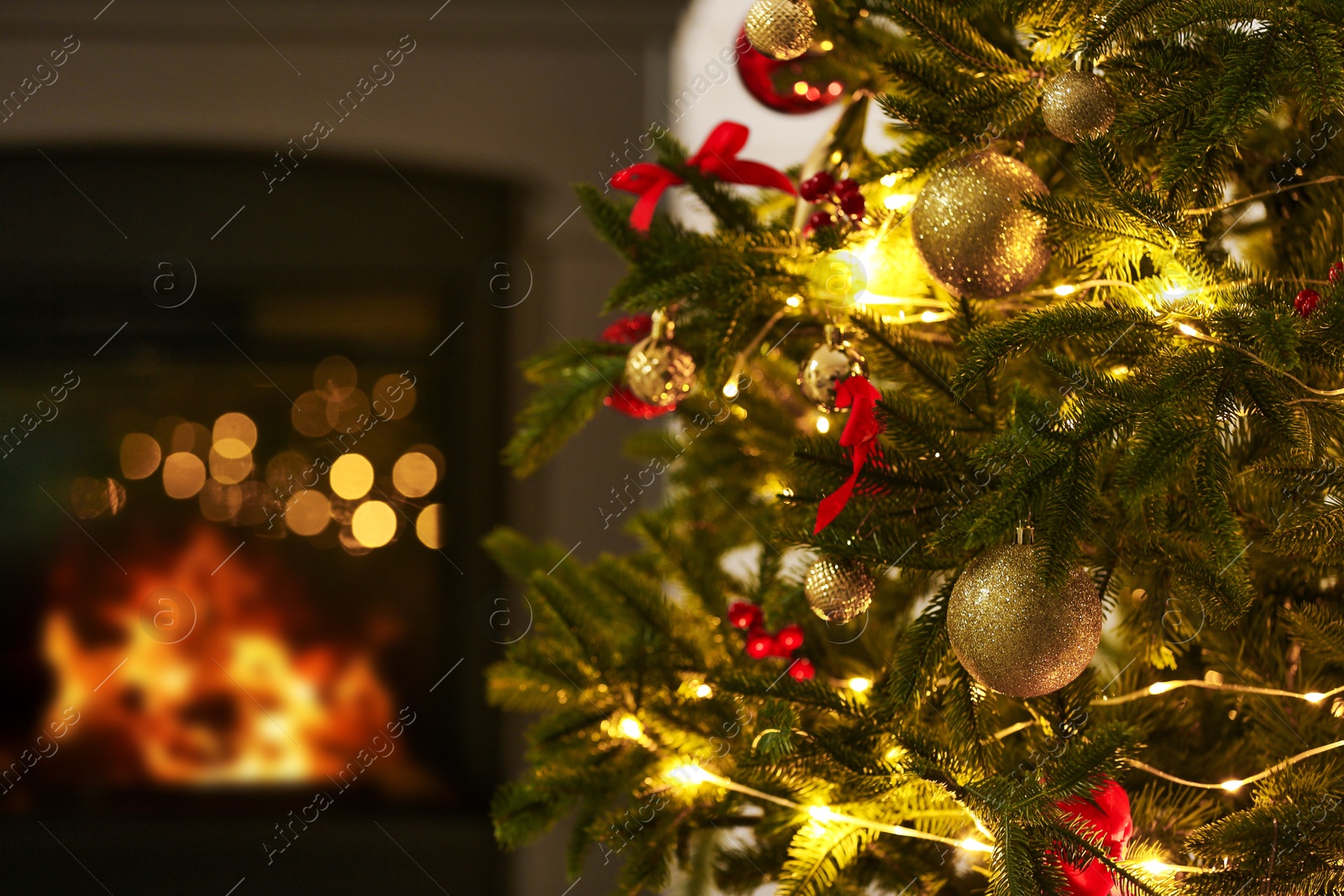 Photo of Beautiful decorated Christmas tree near fireplace at home, closeup. Bokeh effect