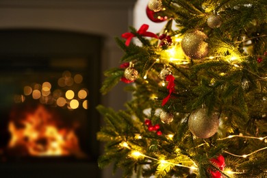 Photo of Beautiful decorated Christmas tree near fireplace at home, closeup. Bokeh effect