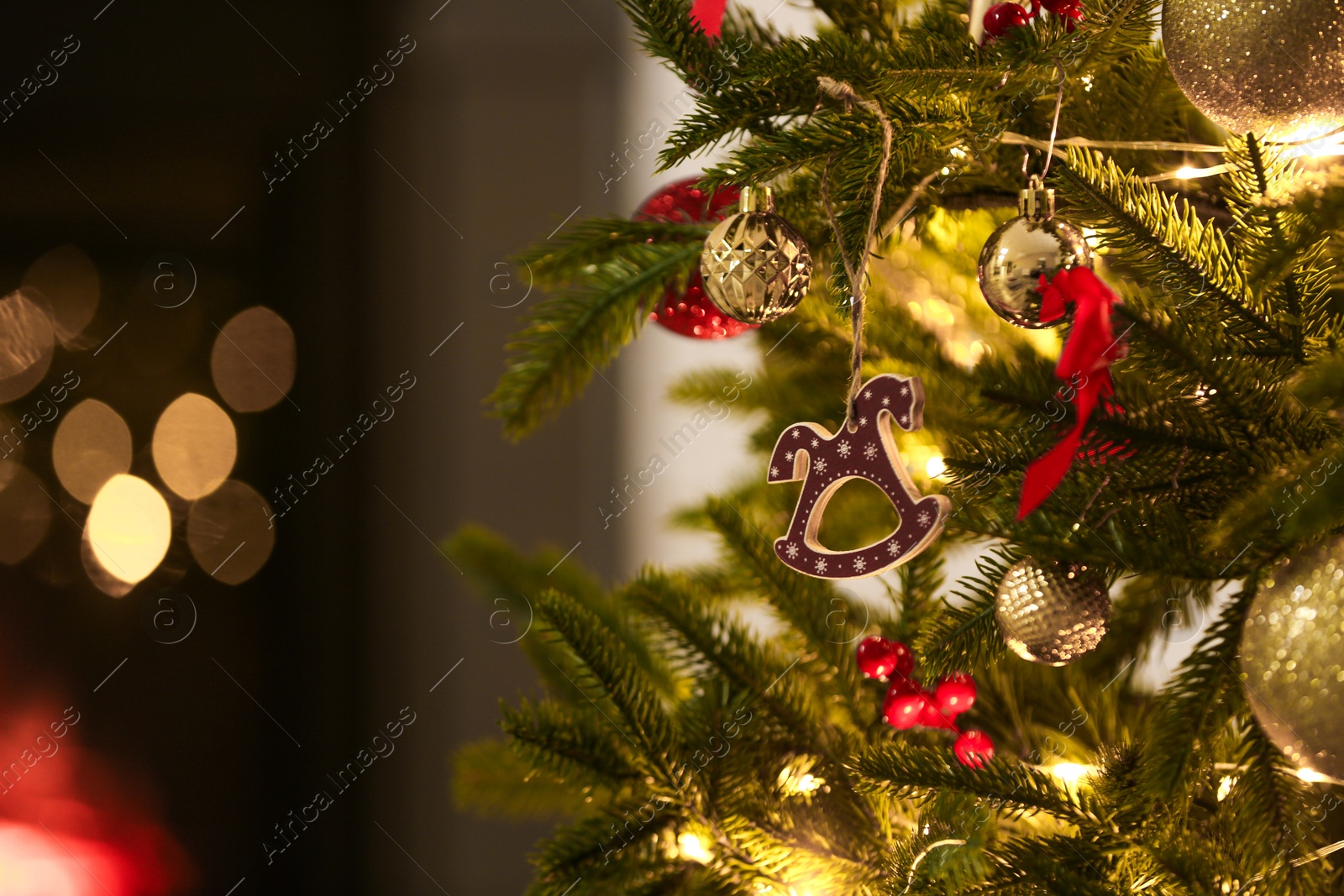 Photo of Beautiful Christmas tree decorated with horse toy, other ornaments and festive lights indoors, closeup. Bokeh effect