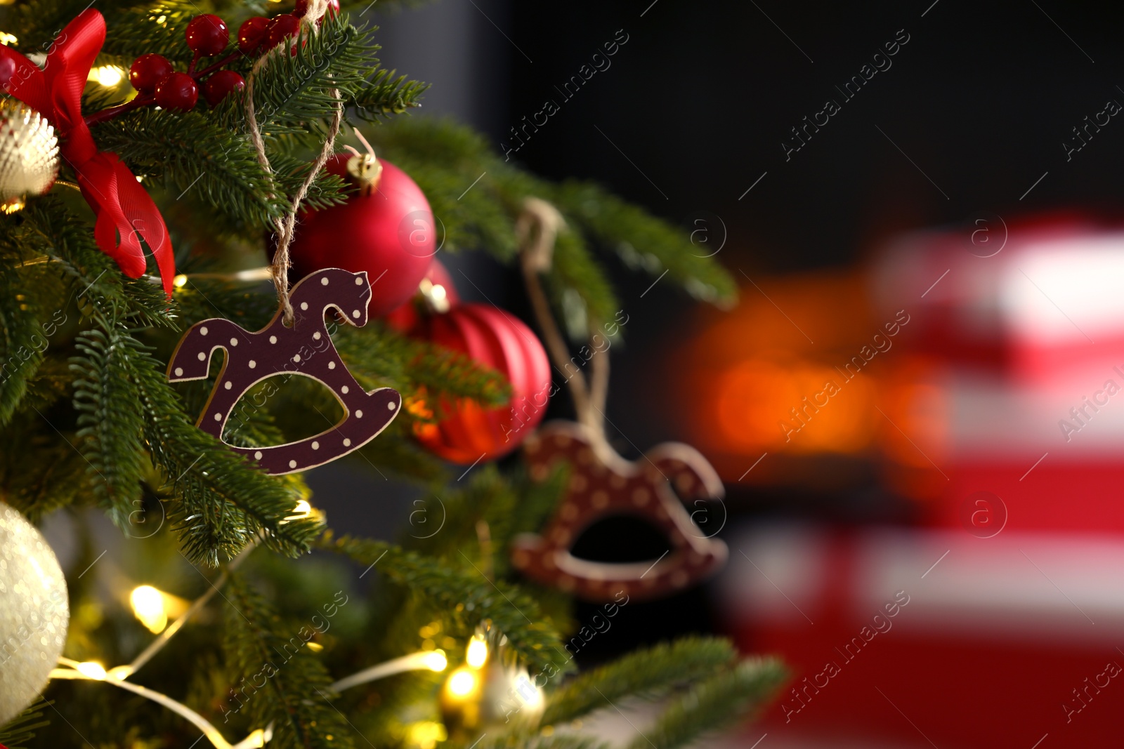 Photo of Beautiful Christmas tree decorated with horse toy, other ornaments and festive lights indoors, closeup. Space for text