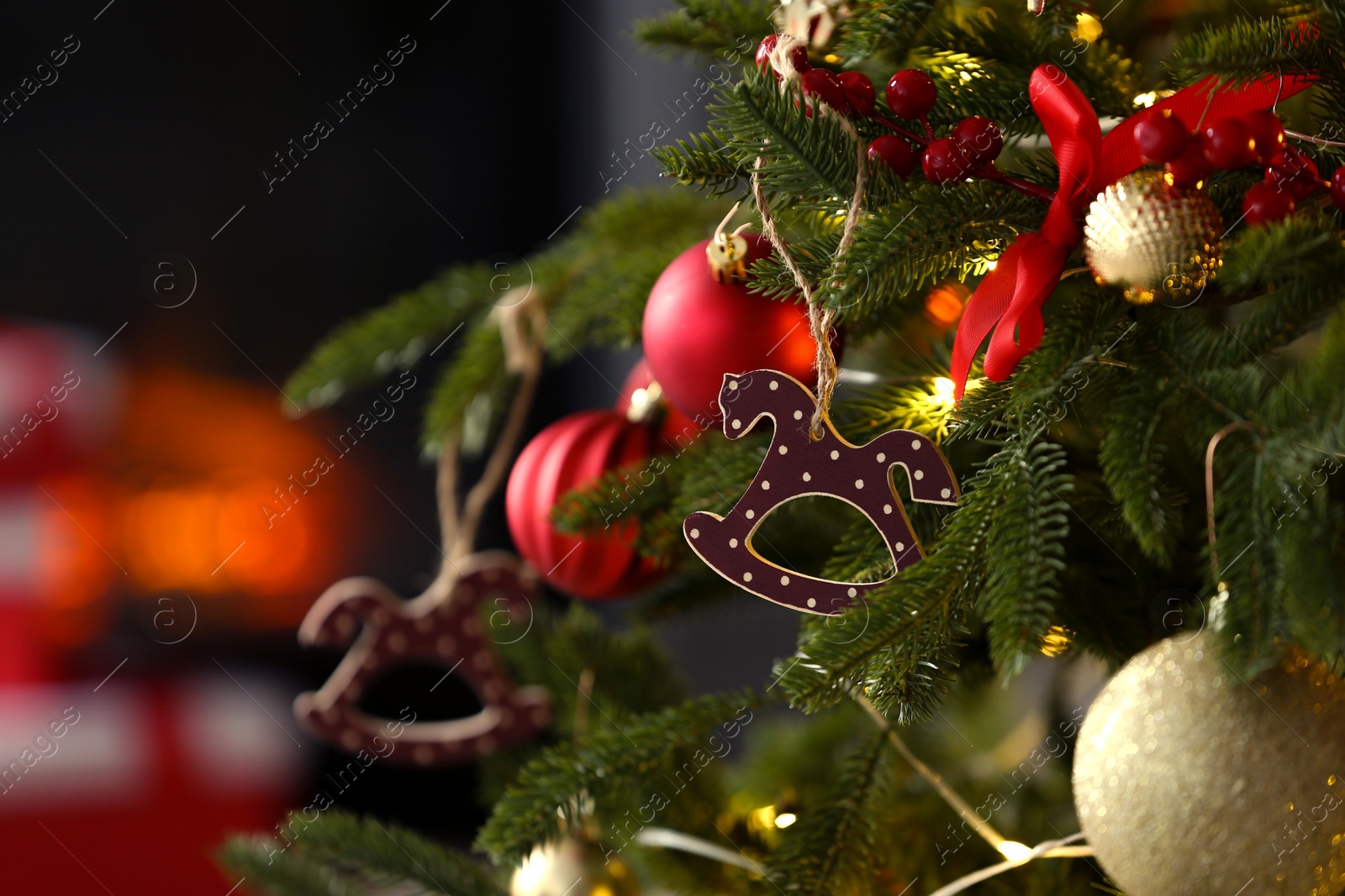 Photo of Beautiful Christmas tree decorated with horse toy, other ornaments and festive lights indoors, closeup. Space for text