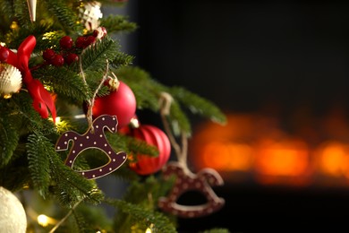 Photo of Beautiful Christmas tree decorated with horse toy, other ornaments and festive lights indoors, closeup. Space for text