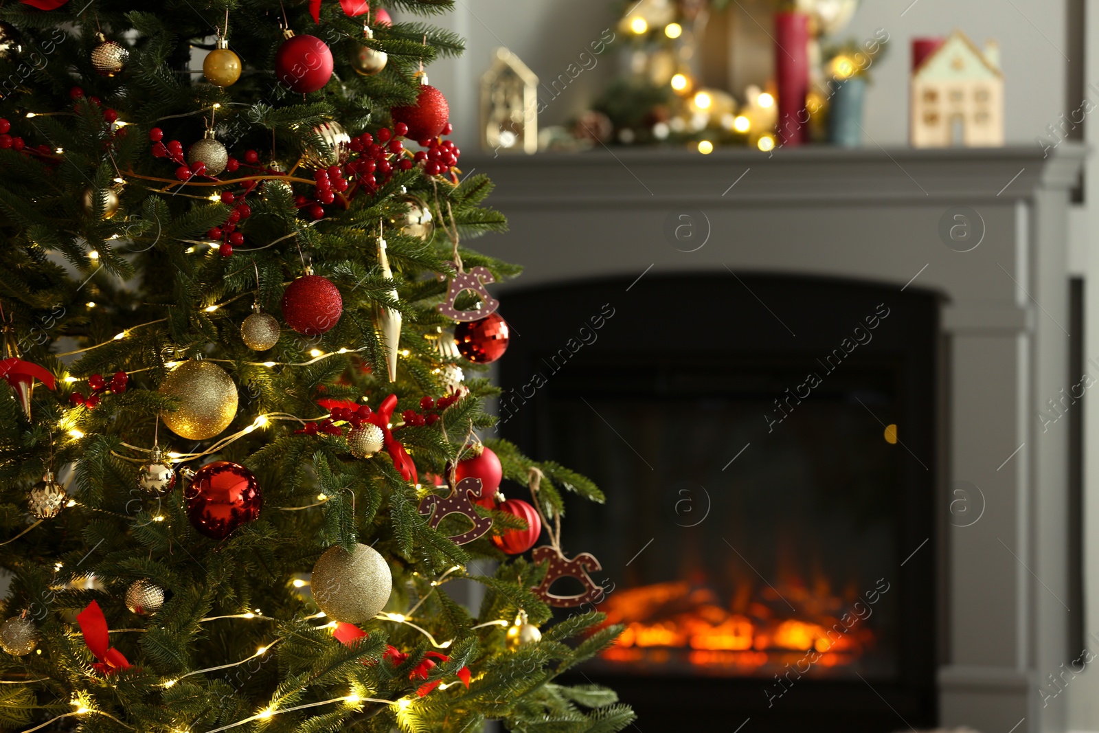 Photo of Beautiful decorated Christmas tree near fireplace at home, closeup. Space for text