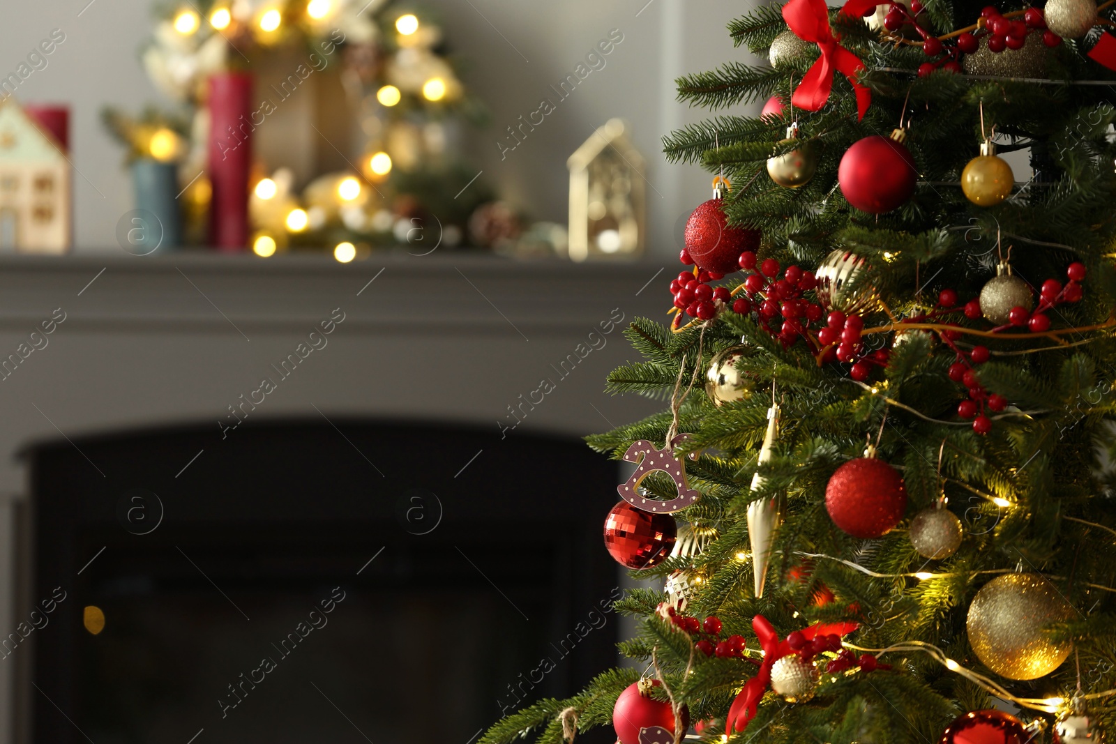 Photo of Beautiful decorated Christmas tree near fireplace at home, closeup. Space for text