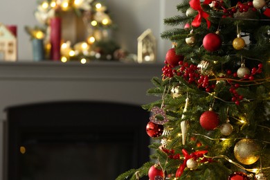 Photo of Beautiful decorated Christmas tree near fireplace at home, closeup. Space for text