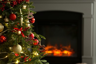 Photo of Beautiful decorated Christmas tree near fireplace at home, closeup. Space for text