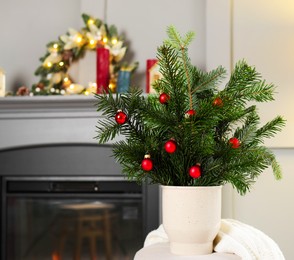 Photo of Beautiful Christmas composition of decorated fir tree branches on pouf indoors