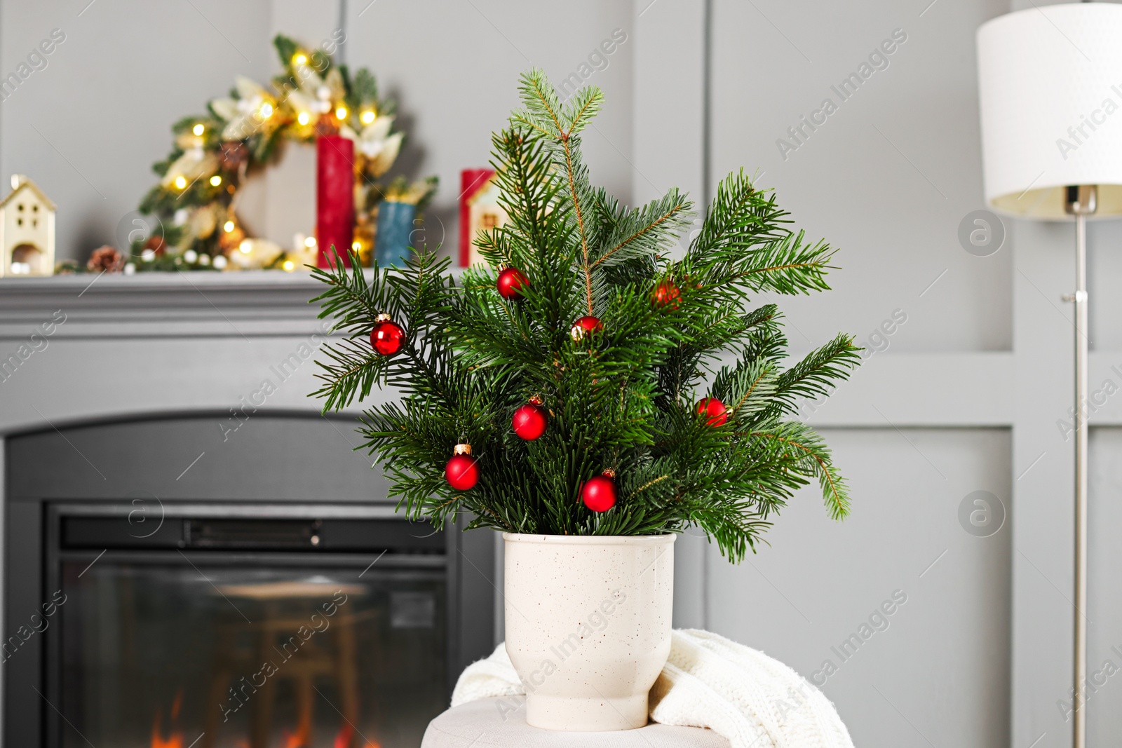 Photo of Beautiful Christmas composition of decorated fir tree branches on pouf indoors