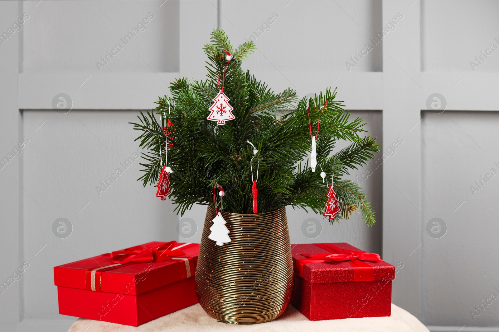 Photo of Beautiful decorated fir tree branches and Christmas gifts on pouf indoors