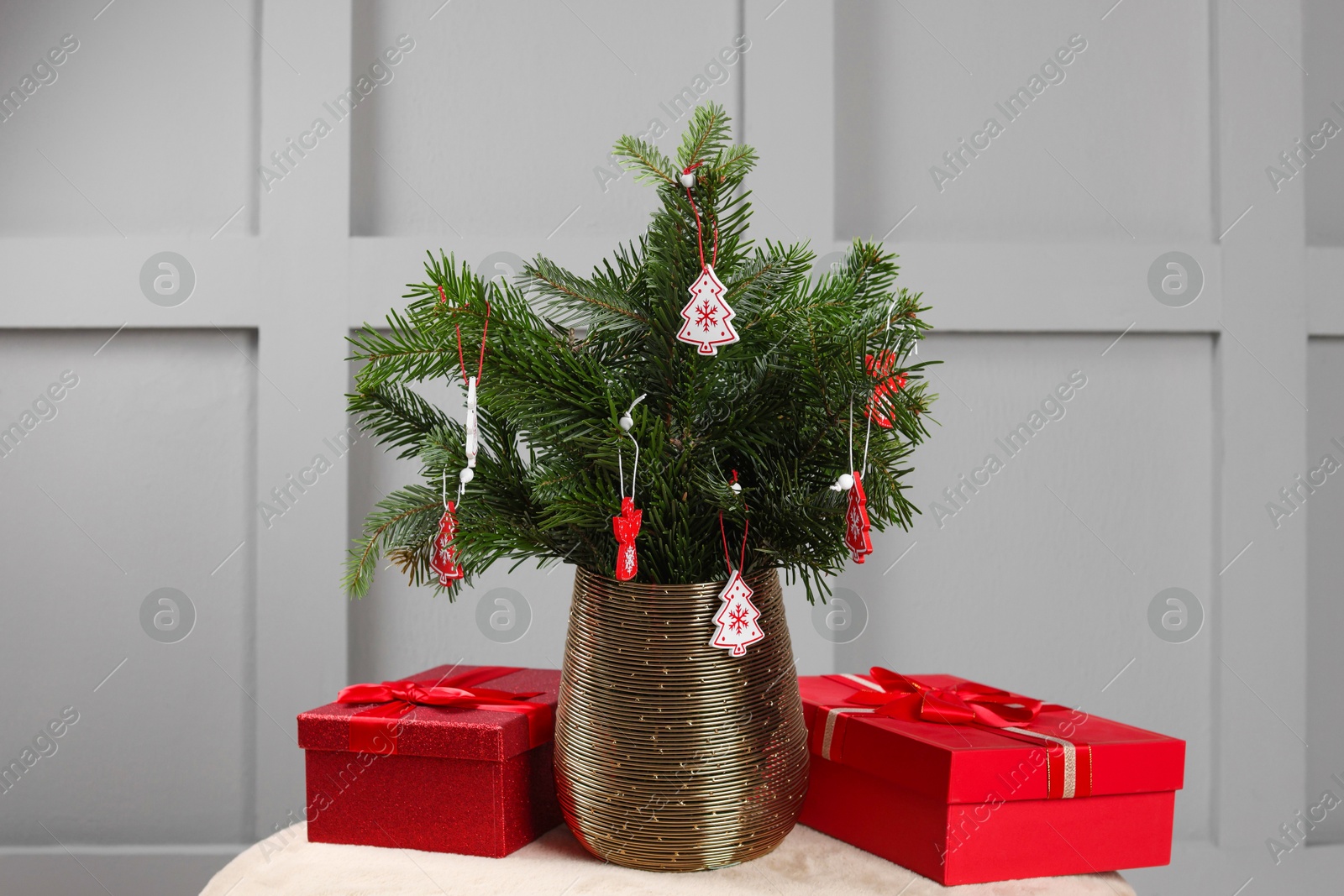 Photo of Beautiful decorated fir tree branches and Christmas gifts on pouf indoors