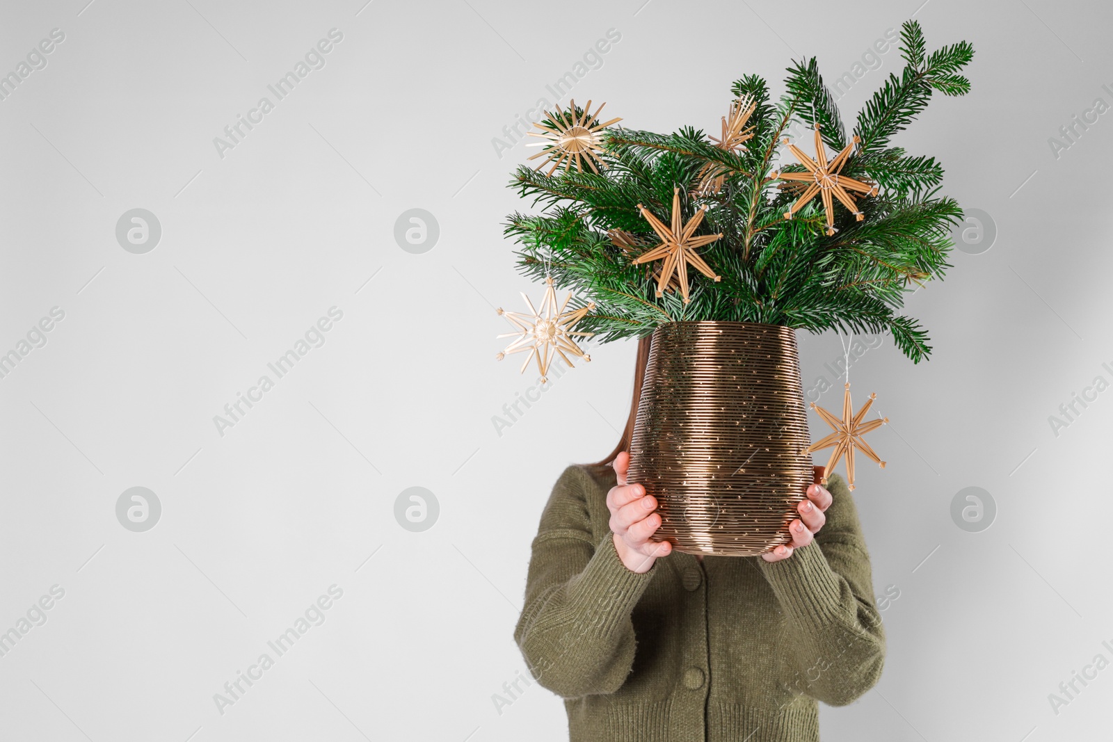 Photo of Woman holding beautiful Christmas composition of decorated fir tree branches on light background. Space for text